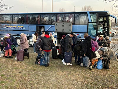 refugees wait to board a bus